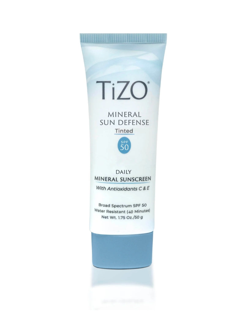 A tube of TiZO Mineral Sun Defense SPF 50 with a sheer tint, in a light blue and white packaging.