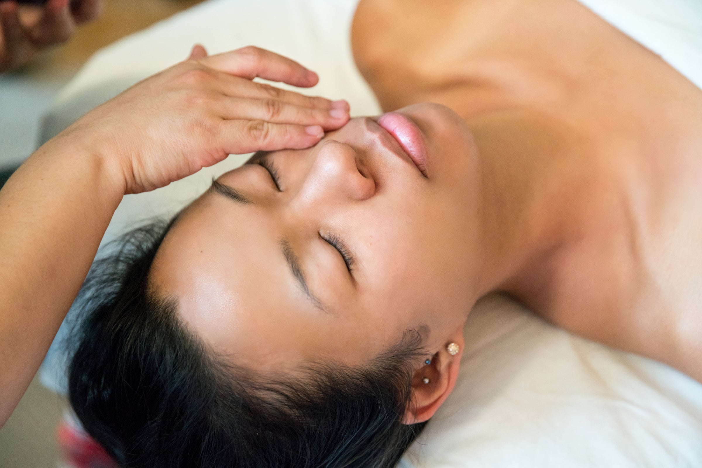 Woman receiving facial with a hand applying Eminence product to her face